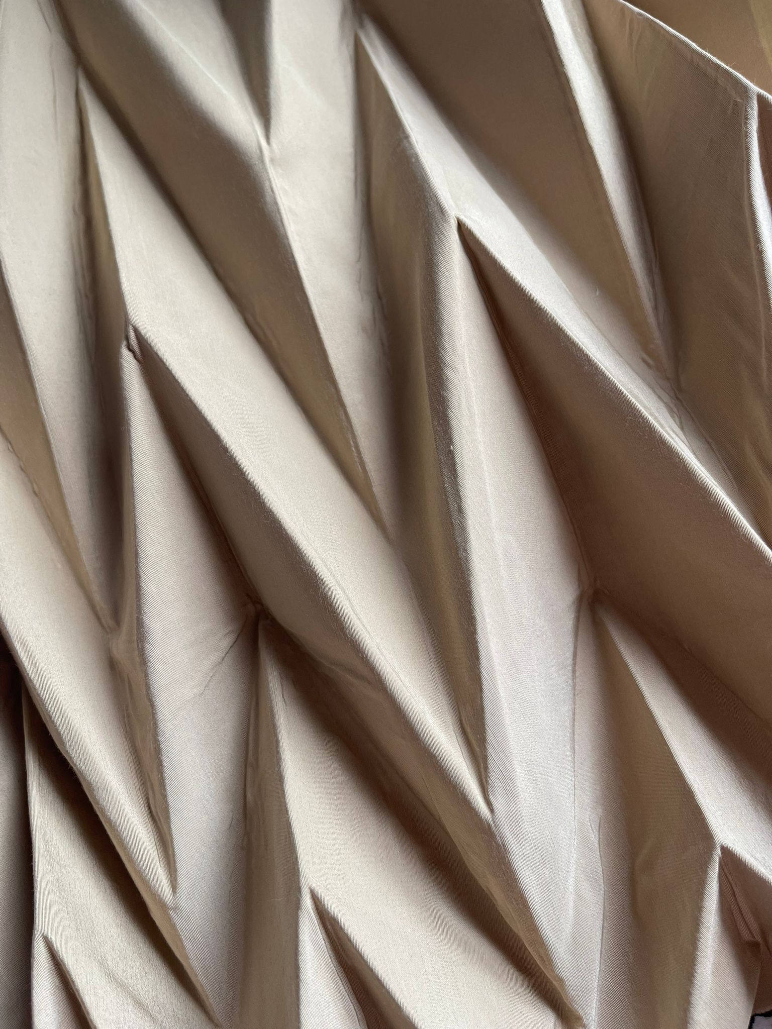PAUX — Close-up of precisely folded chevron pleats in cream fabric